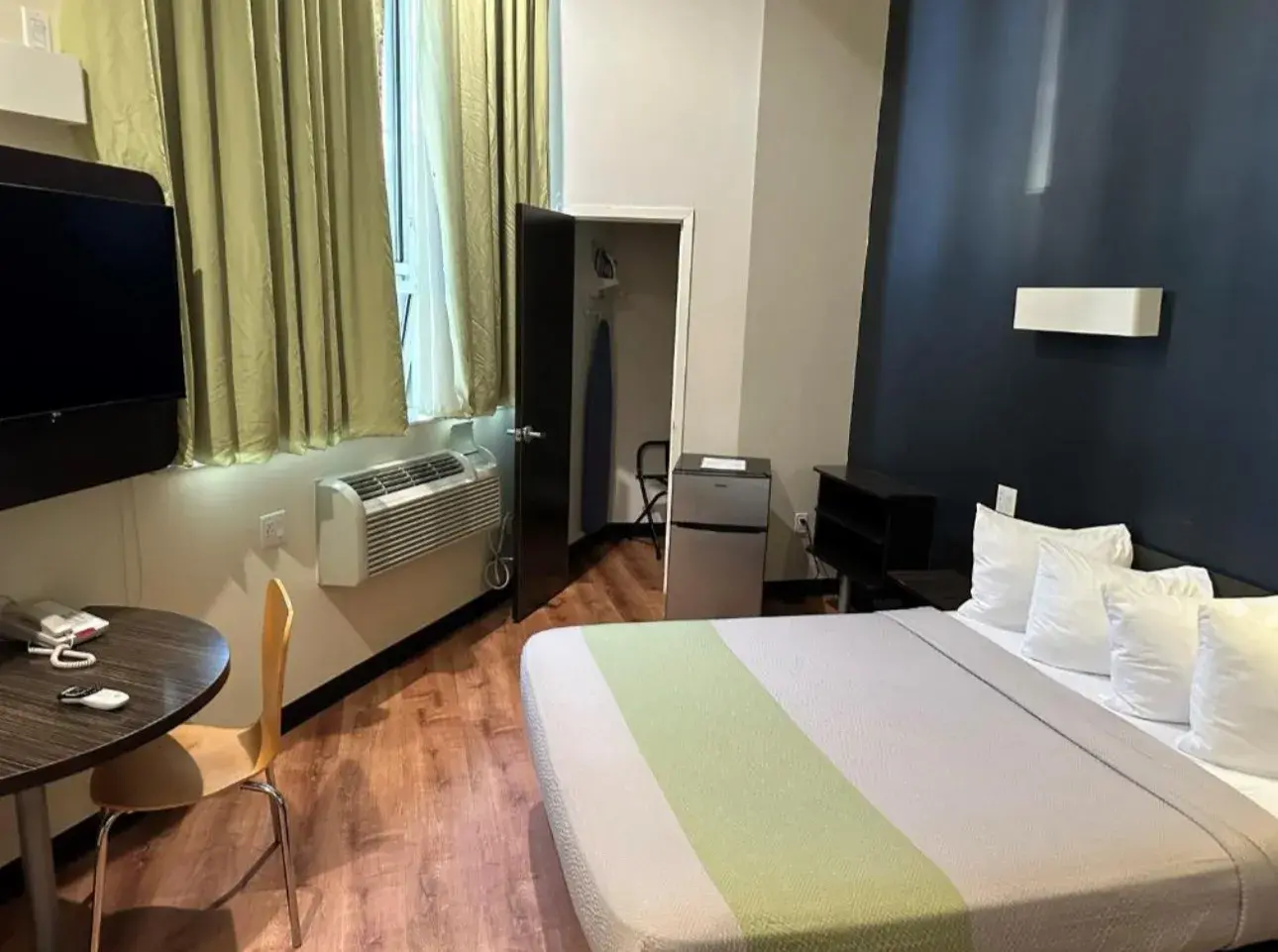 King Room with a blue wall, closet with ironing board and mini-fridge