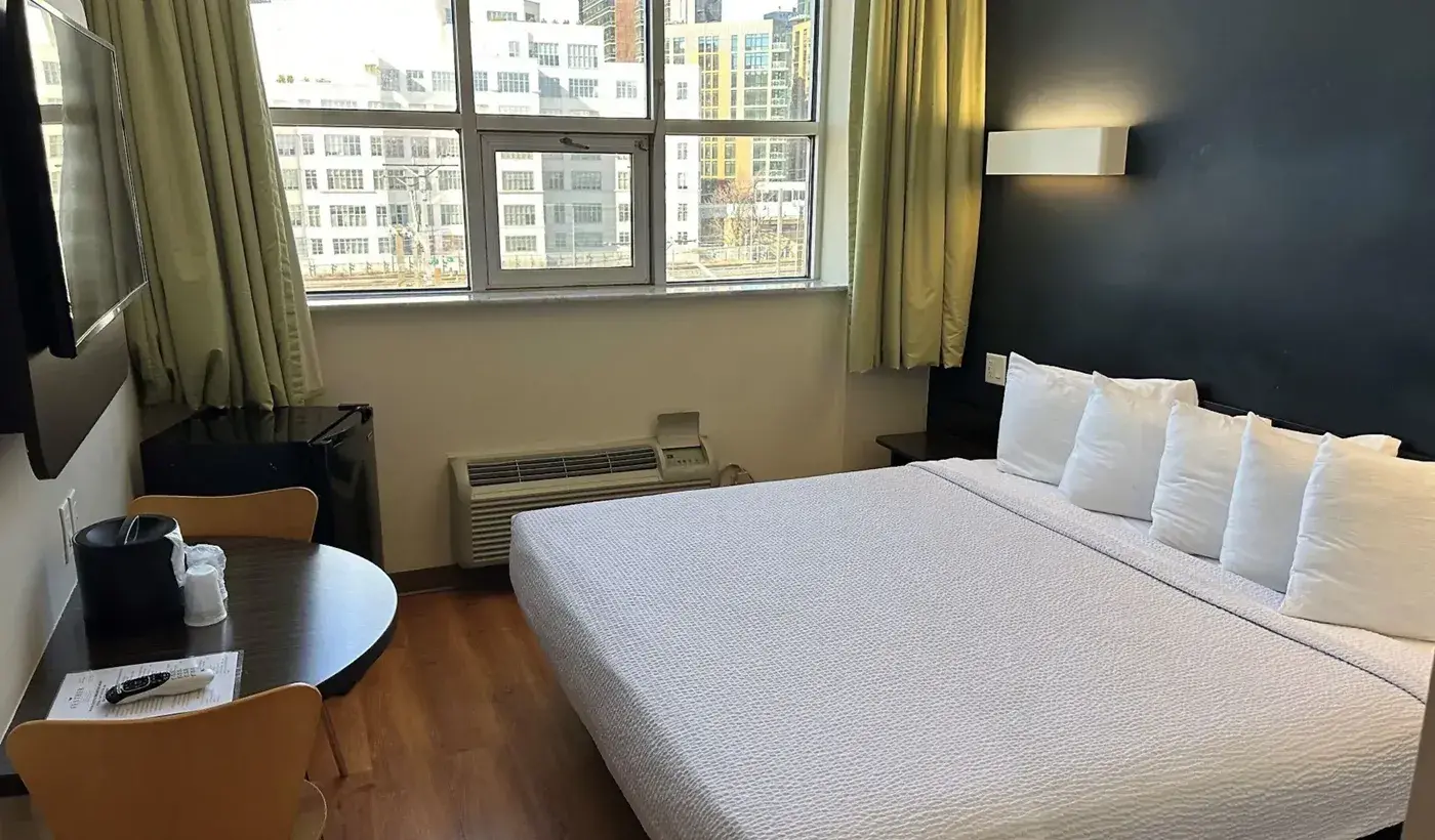 Queen Room at Feather Factory Hotel with a round table and large window facing city buildings