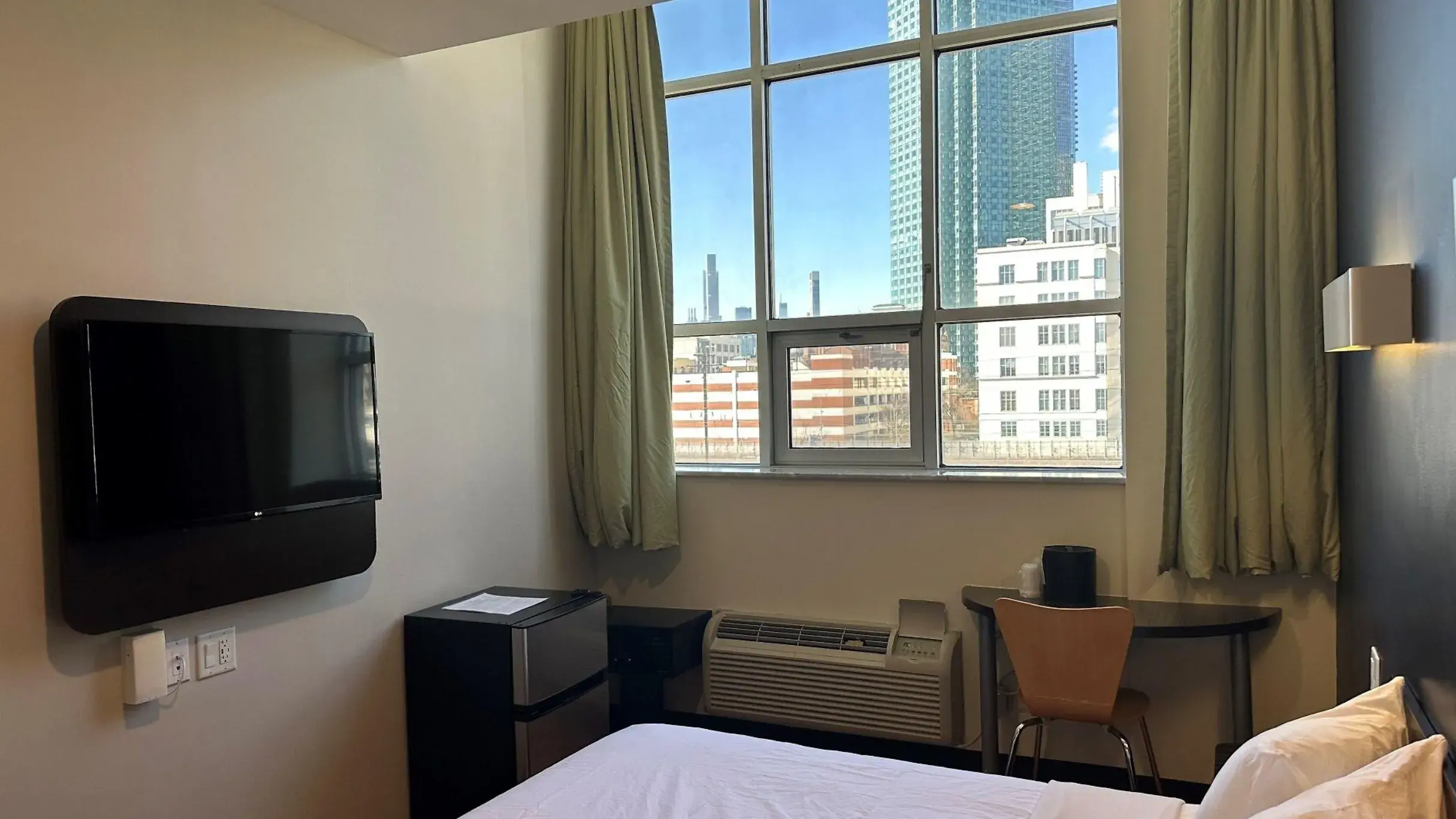 Accessible room with a large window facing high-rises, TV, mini-fridge and desk
