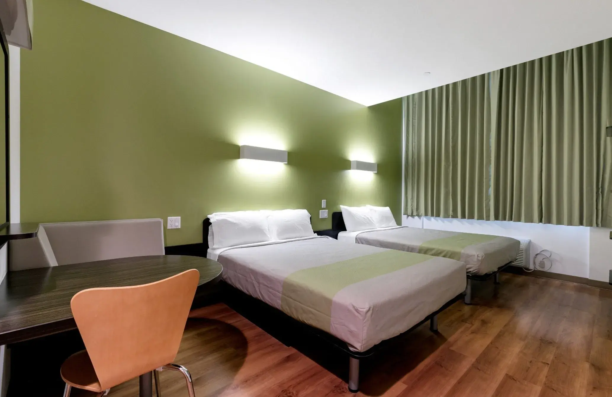 Room with two double beds, a round table and a chair