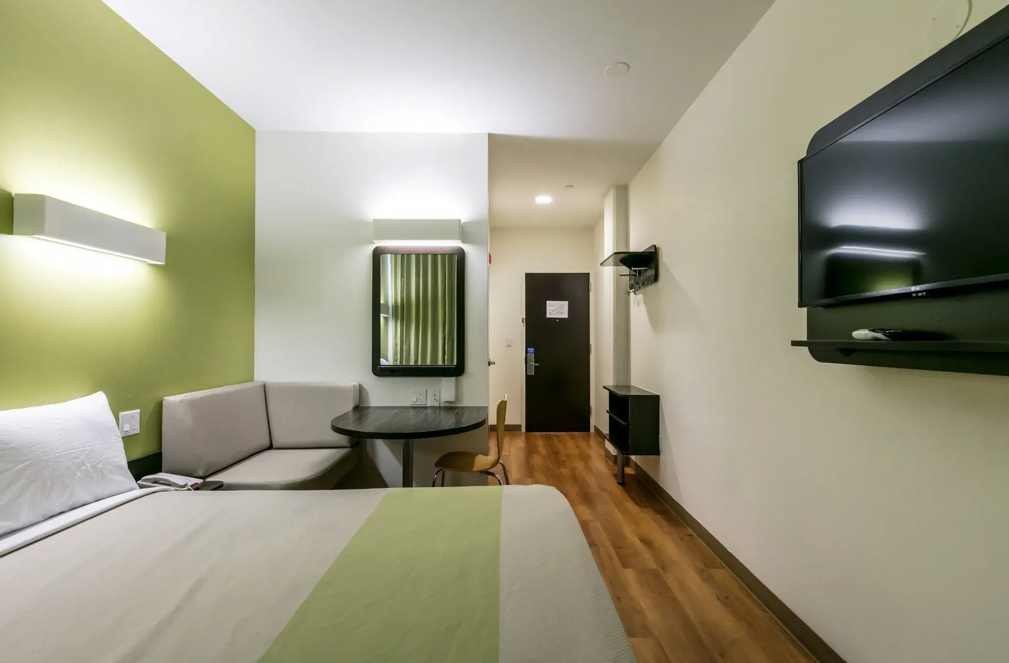Room with a sofa corner, table and TV, looking toward the entrance door